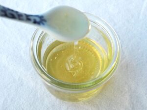 ガラス容器に入れたはちみつをスプーンですくっている様子