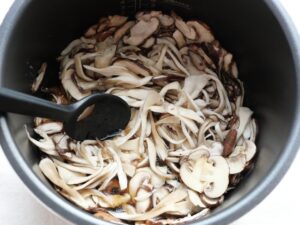 低温調理後のきのこをスプーンでやさしくかき混ぜ、調味液をなじませている様子