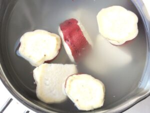 一口大の乱切りで面取りをしたさつまいもがボウルの水に浸されている状態