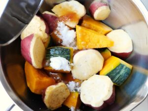 さつまいもとかぼちゃの上に砂糖と醤油、水を加えている様子