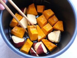 菜箸でかぼちゃの位置を調整している様子。皮を下にして並べ直している