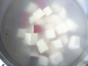 皮付きで角切りにしたさつまいもを水にさらしている様子。さつまいもの砂糖バターの下ごしらえ