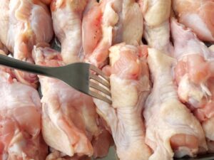 鶏手羽元にフォークで穴を開けて下ごしらえしている様子（電気圧力鍋で調理する前）