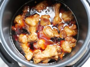 鶏手羽元の甘辛煮を電気圧力鍋の煮汁に浸けて味をなじませている様子（煮込み後）