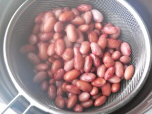 ゆでこぼしてアクを抜いた金時豆をざるに上げたところ。皮がふくらみ、しわがほとんどない状態