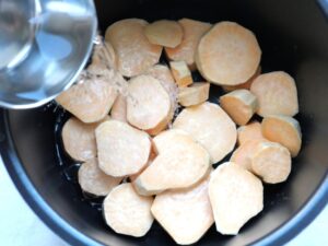 電気圧力鍋の内釜のさつまいもに水をまわしかけているところ