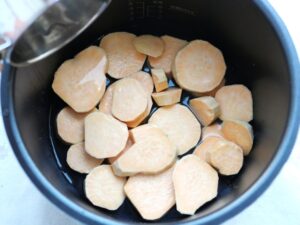 電気圧力鍋の内釜に水を注ぎ終わったところ。釜底のさつまいもだけが水に浸った状態