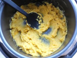 電気圧力鍋の内釜でシリコンスプーンでさつまいもをなめらかに潰している様子