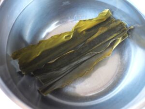 水を張ったボウルに乾燥昆布を浸して戻している様子。昆布の煮物の下ごしらえ工程