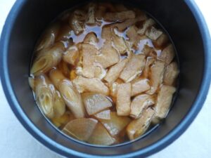 内鍋の煮汁の中で醤油味がしみた大根、長ねぎ、油揚げ