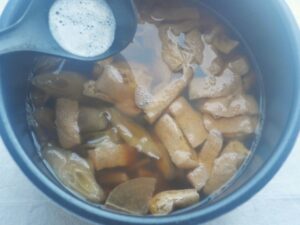 煮込みが終わり、白い泡状のアクをお玉ですくっている様子