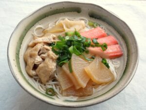 器に盛り付けたにゅうめん。大根、長ねぎ、油揚げに、かにかま、小口ねぎも添えた盛り付け例