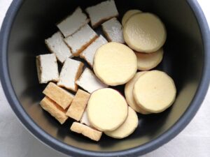 厚揚げの横にさつまいもを並べ入れた様子。電気圧力鍋の内釜の中