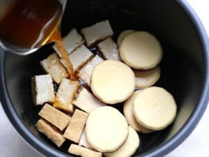 電気圧力鍋の内釜に調味料を混ぜた煮汁を注いでいる様子