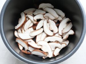 電気圧力鍋の内釜にしいたけの薄切りを敷き詰めた状態