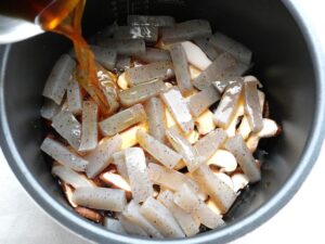 電気圧力鍋の内釜に調味料を混ぜた煮汁を注いでいるところ