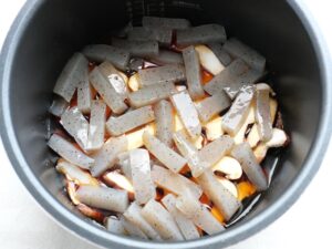加圧前の電気圧力鍋の中。煮汁に半分浸かったこんにゃくとしいたけ