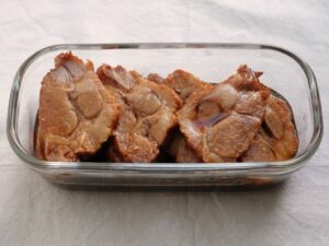 保存容器に入れた煮豚のスライス。煮汁に浸けた冷蔵保存前の状態