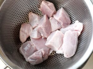 ざるに上げた湯通し後の豚肉