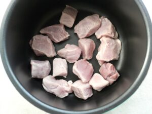 電気圧力鍋の内釜に湯通しした豚肉を並べ入れたところ。角煮風の仕上がりにするための手順