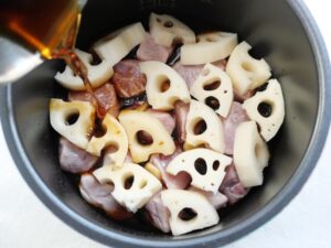 電気圧力鍋の内釜に水・醤油・砂糖・みりんを混ぜた煮汁を注いでいる様子