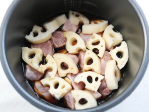 電気圧力鍋の釜底に並べた豚肉が煮汁に浸っている様子