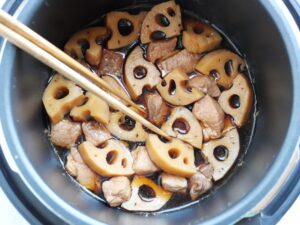 れんこんを菜箸で裏返して煮汁に浸け、煮込む準備