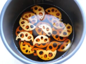 内釜に煮汁を加え、れんこんが煮汁に沈んでいる様子