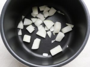 電気圧力鍋の内釜に入れた角切り玉ねぎ。無水調理の準備
