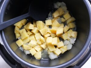 スプーンで電気圧力鍋の具材をかきまぜている様子