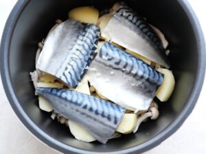 塩さばの上ににんにくを散らした様子(電気圧力鍋内)