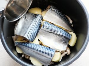 塩さばと野菜に、酒と水を混ぜた煮汁をまわしかけているところ