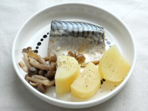 塩さばの蒸し料理を皿に盛り付けた様子、じゃがいもとしめじには塩・こしょうをふった状態