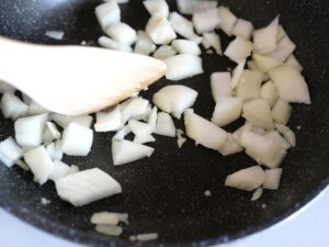 フライパンで角切りの玉ねぎを中火で炒めているところ