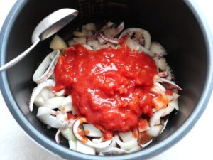 炒めたイカと玉ねぎの上にカットトマトをのせ、白ワインを加えたところ