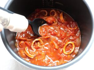 加圧調理を終えたイカのトマト煮に、こしょうを振っているところ