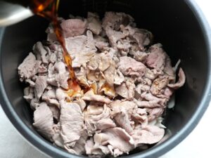 電気圧力鍋の内釜に調味料を混ぜた煮汁を注いでいるところ