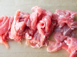 まな板の上で豚薄切り肉を一口大に切った状態