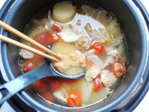 電気圧力鍋にお玉と菜箸で味噌を溶き入れている様子