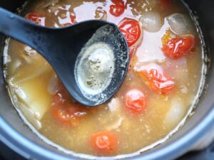 豚汁の表面に浮いたアクをお玉ですくっているところ（煮込み停止直前）