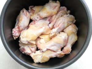 電気圧力鍋の内釜に下ごしらえした鶏手羽元を並べたところ