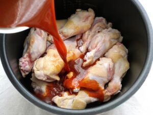 調味料を混ぜた煮汁を電気圧力鍋に注いでいるところ（加圧調理前）