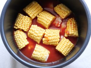 煮汁を注ぎ終えた電気圧力鍋の中。とうもろこしの実が煮汁から出ている様子