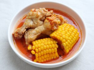 赤いスープとともに盛り付けられた鶏手羽元ととうもろこしのケチャップ煮。お肉がしっとり仕上がっている