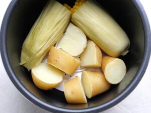 電気圧力鍋で加圧調理した後のじゃがいもととうもろこし。とうもろこしの皮がしんなりとして、火が通った様子