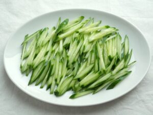 千切りにしたきゅうりを皿に敷き詰めた盛り付け準備