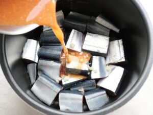 さんまと、にんにくのすりおろしの上から、煮汁を注ぎ入れているところ。中華風味噌煮の下準備