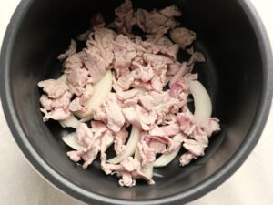 電気圧力鍋の内釜に玉ねぎと炒めた豚肉を重ね入れた状態