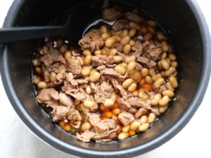 圧力調理後の豚肉と大豆をスプーンでやさしく混ぜている様子