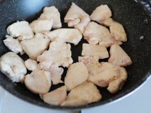 小麦粉をまぶした鶏むね肉の両面を、フライパンで軽く焼いている工程